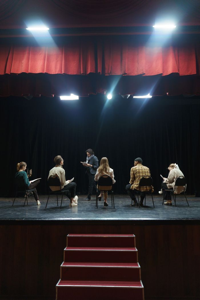 A group of actors rehearsing on stage under spotlights, creating an immersive theater experience.